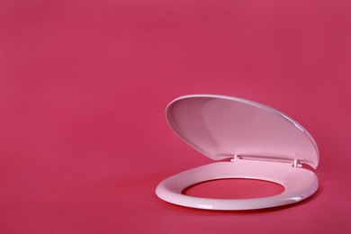 Photo of New plastic toilet seat on pink background, space for text