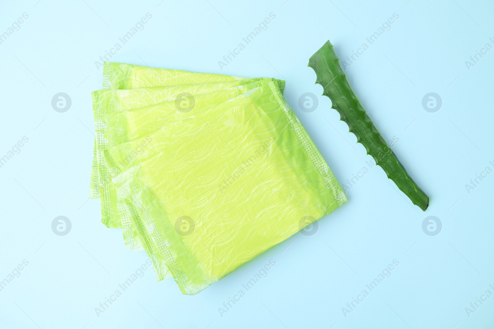 Photo of Flat lay composition with menstrual pads and aloe leaf on color background. Gynecological care