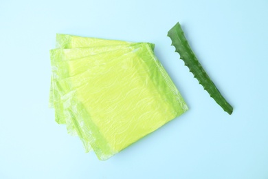 Photo of Flat lay composition with menstrual pads and aloe leaf on color background. Gynecological care