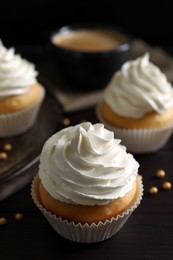 Photo of Delicious cupcakes with white cream on wooden table, closeup