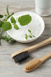 Photo of Toothbrushes, green herbs and sea salt on wooden table, above view