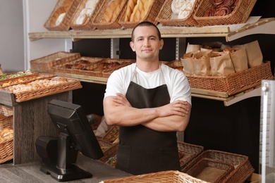 Photo of Portrait of professional baker at cashier desk near showcase in store