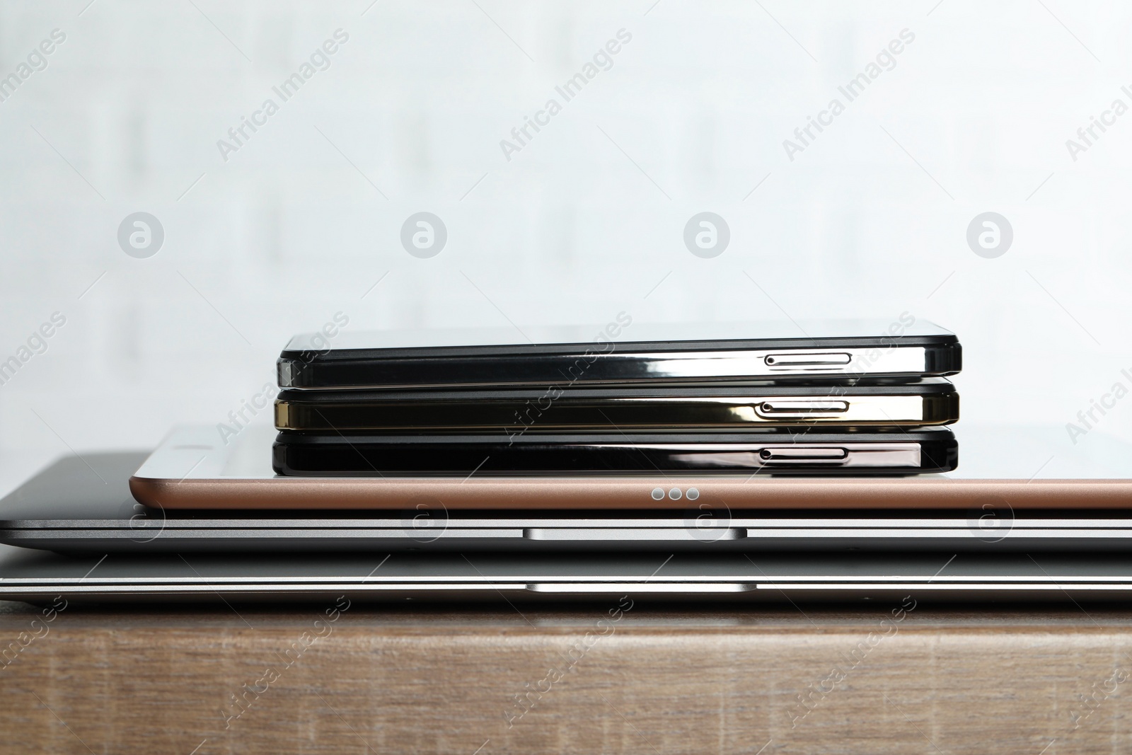 Photo of Stack of electronic devices on wooden table, closeup