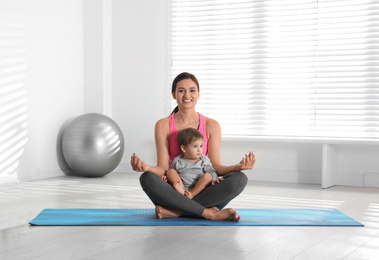 Photo of Young woman meditating with her son at home