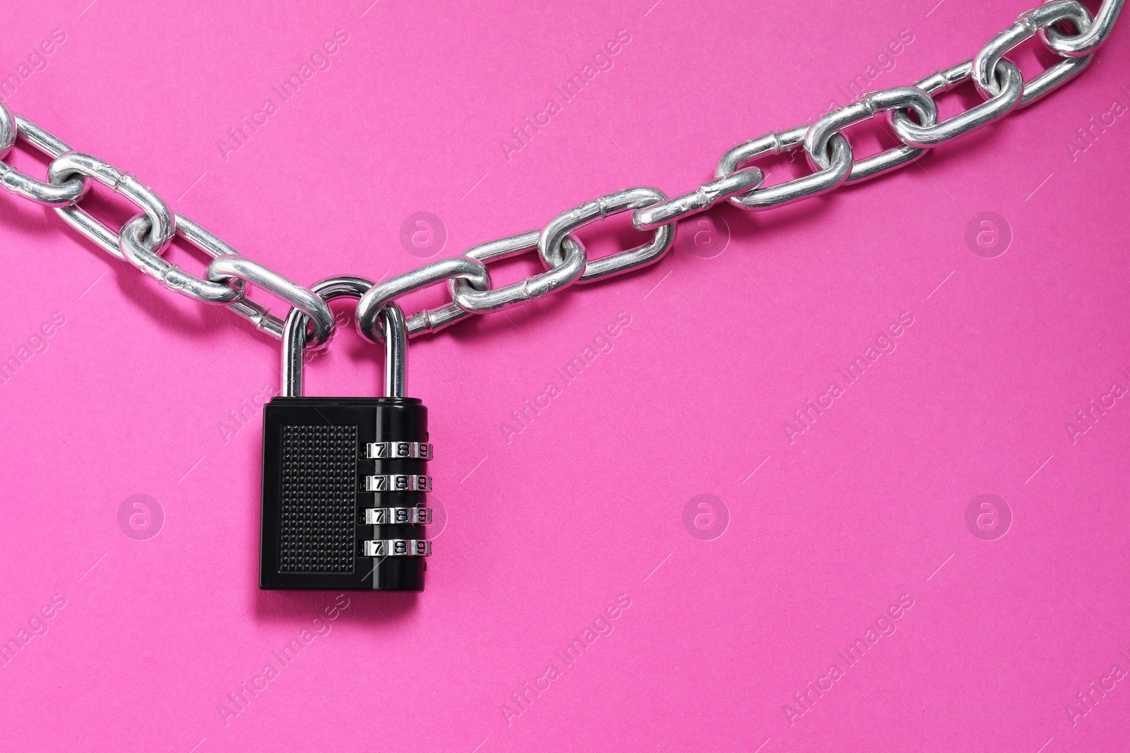 Photo of Steel combination padlock and chain on pink background, top view. Space for text