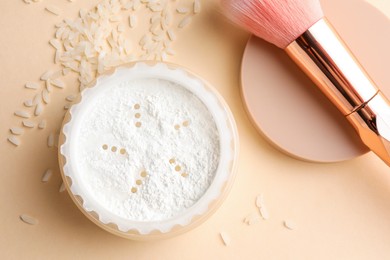 Loose face powder, rice and makeup brush on beige background, flat lay