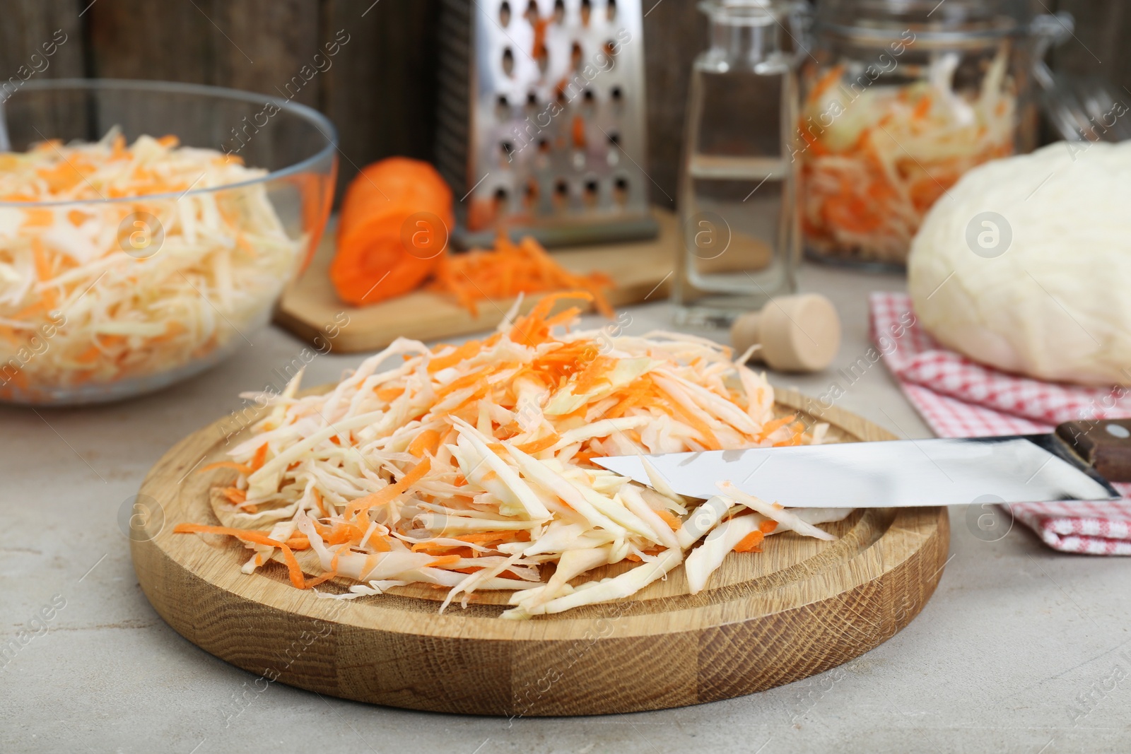 Photo of Cooking delicious sauerkraut soup. Fresh chopped carrot and cabbage on light grey table, closeup