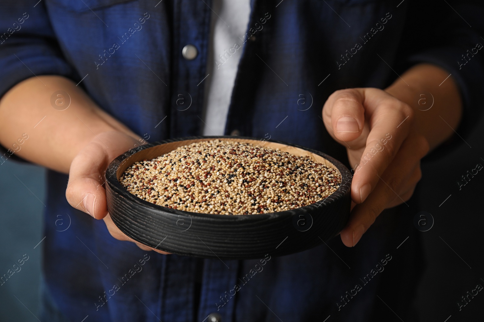 Photo of Woman holding plate with mixed quinoa seeds on color background, closeup