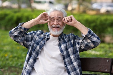 Photo of Portrait of happy grandpa with glasses on bench in park