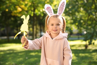 Cute little girl with bunny ears and toy in park. Easter celebration