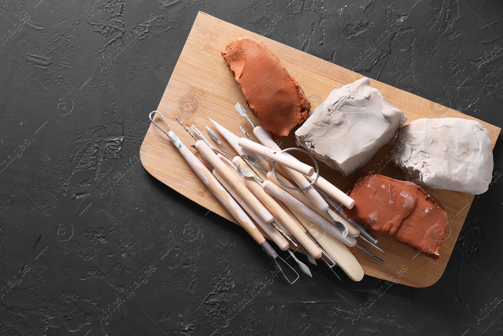 Photo of Clay and set of modeling tools on black table, top view. Space for text