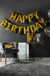 Photo of Room interior with gift boxes and phrase HAPPY BIRTHDAY made of golden balloon letters