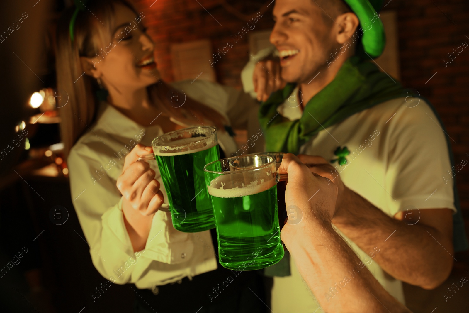 Photo of People with beer celebrating St Patrick's day in pub, focus on hands