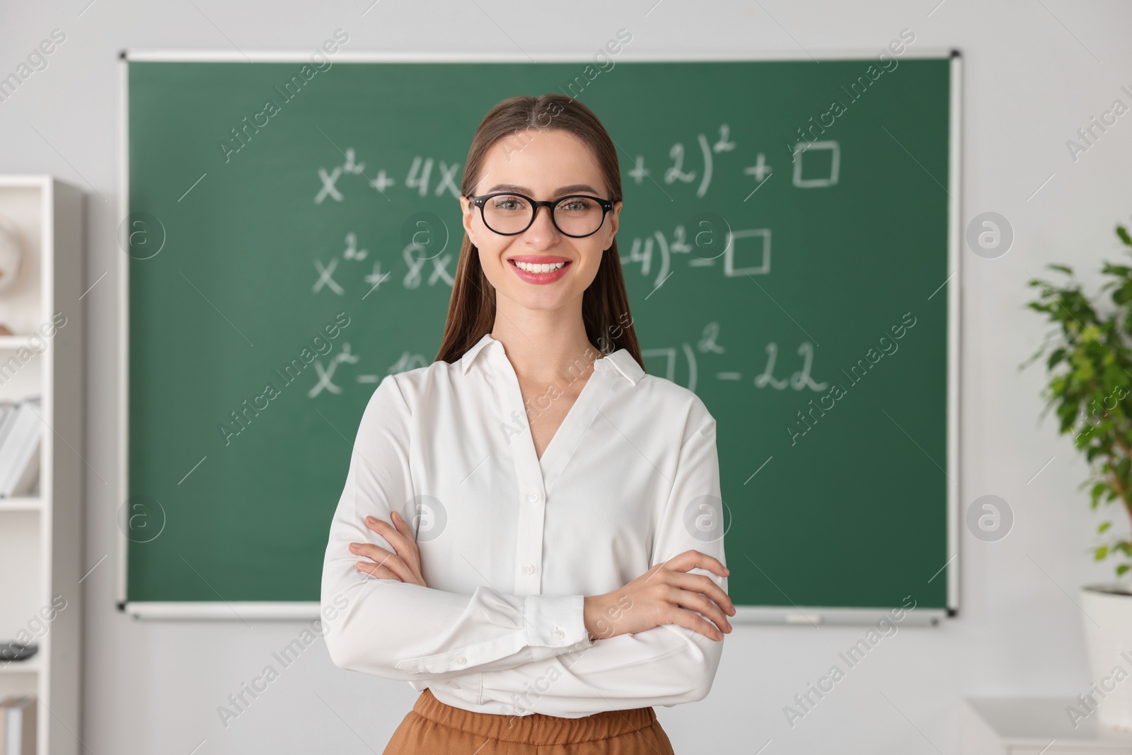 Photo of Portrait of young math’s teacher near chalkboard in classroom