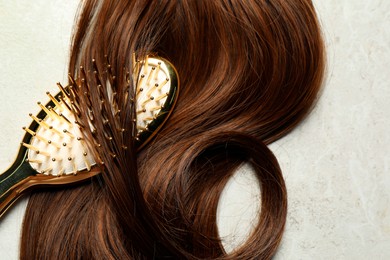 Photo of Stylish brush with brown hair strand on grey table, top view