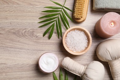 Flat lay composition with spa products and burning candle on light wooden table. Space for text