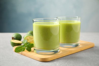 Photo of Fresh feijoa smoothie and fresh mint on grey table, closeup