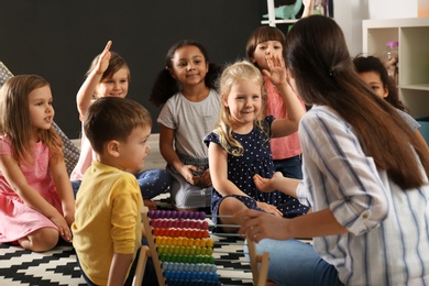 Photo of Cute little children with nursery teacher in kindergarten. Indoor activity