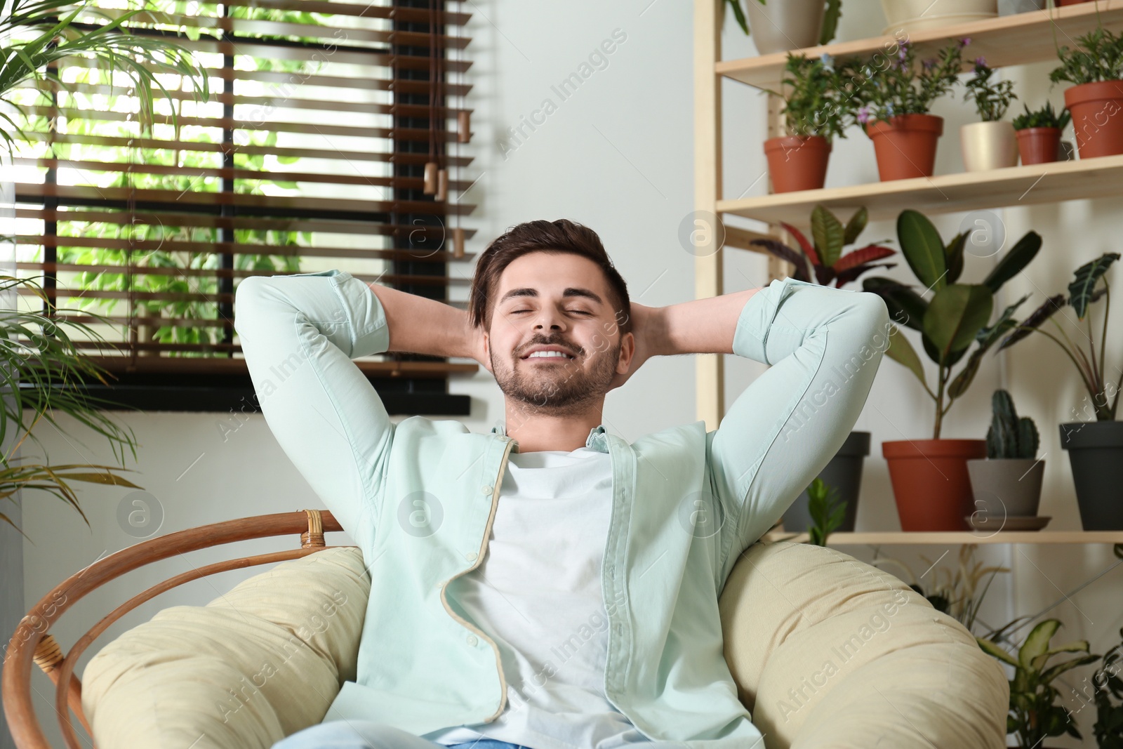 Photo of Young man resting in room with different home plants