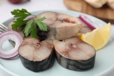 Photo of Slices of tasty salted mackerel with parsley, onion ring and lemon wedge on plate, closeup