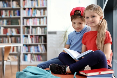 Happy little children reading book in library
