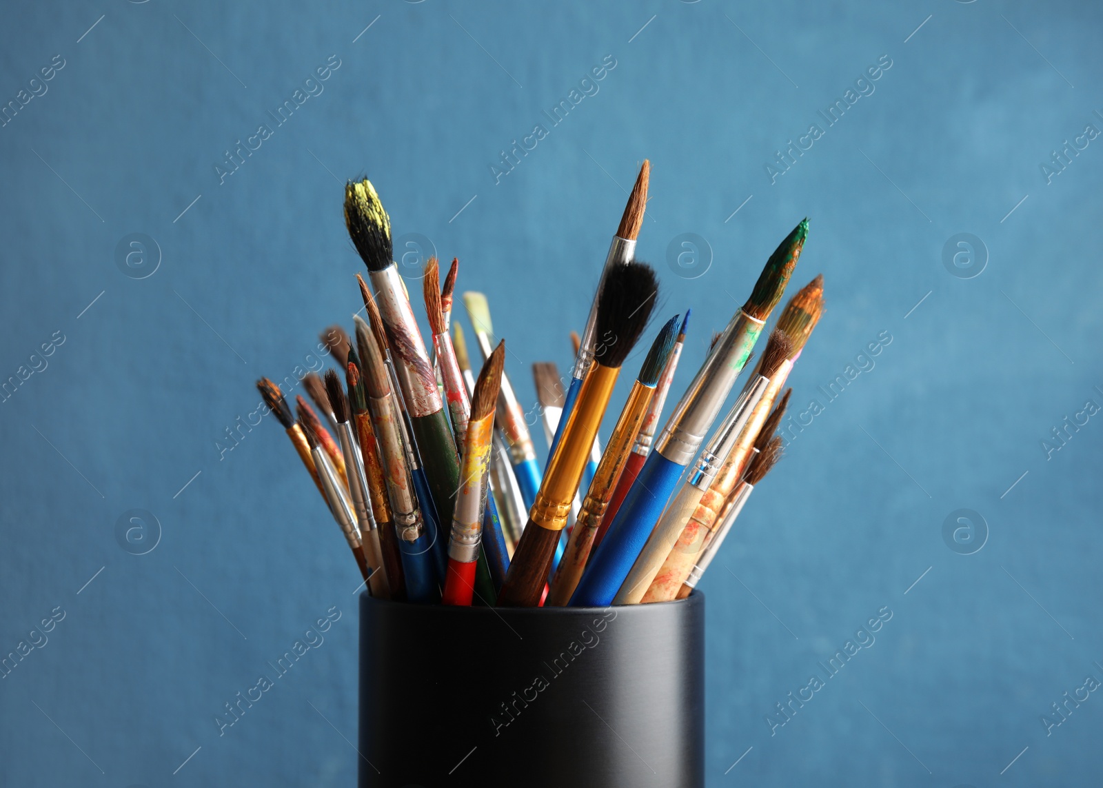 Photo of Holder with paint brushes on color background