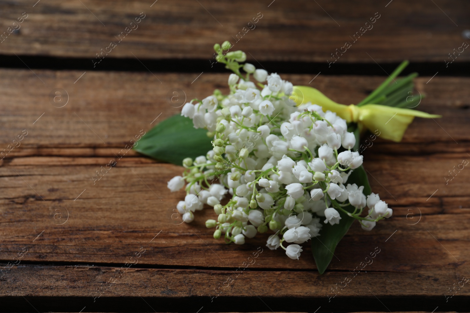 Photo of Beautiful lily of the valley flowers on wooden table