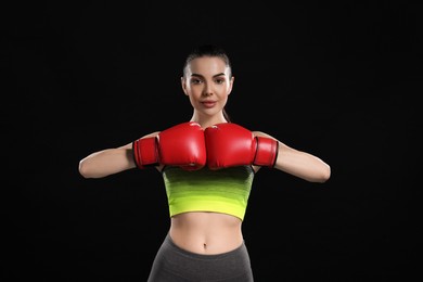 Photo of Portrait of beautiful woman in boxing gloves on black background