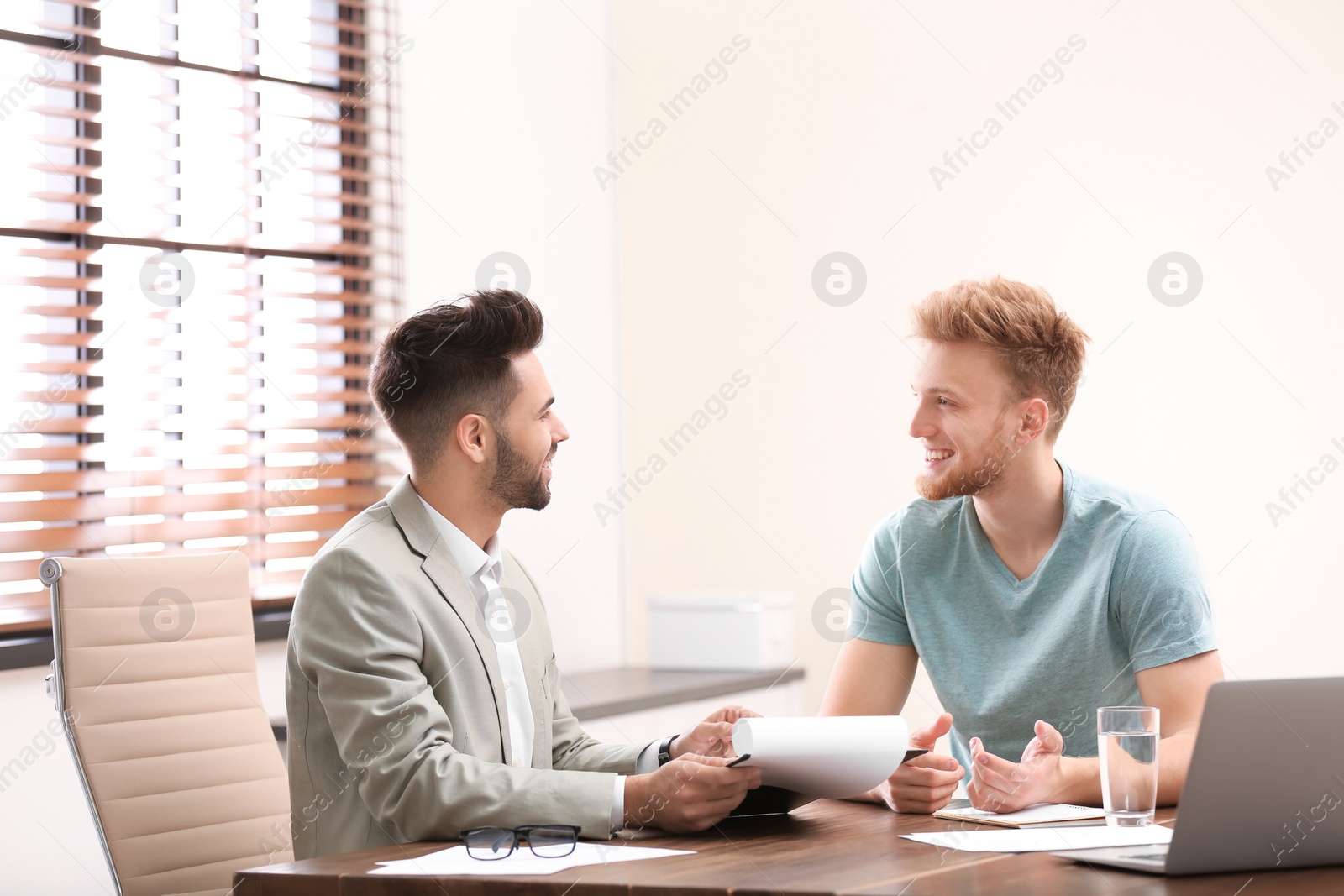 Photo of Insurance agent consulting young man in office