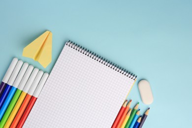 Photo of Flat lay composition with open notebook and other school stationery on light blue background, space for text. Back to school