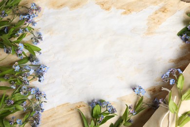 Photo of Beautiful forget-me-not flowers and old parchment, top view