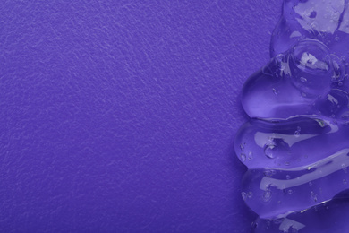Photo of Sample of transparent cosmetic gel on violet background, top view