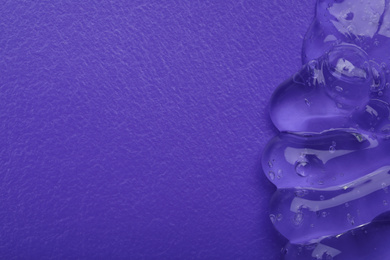 Sample of transparent cosmetic gel on violet background, top view