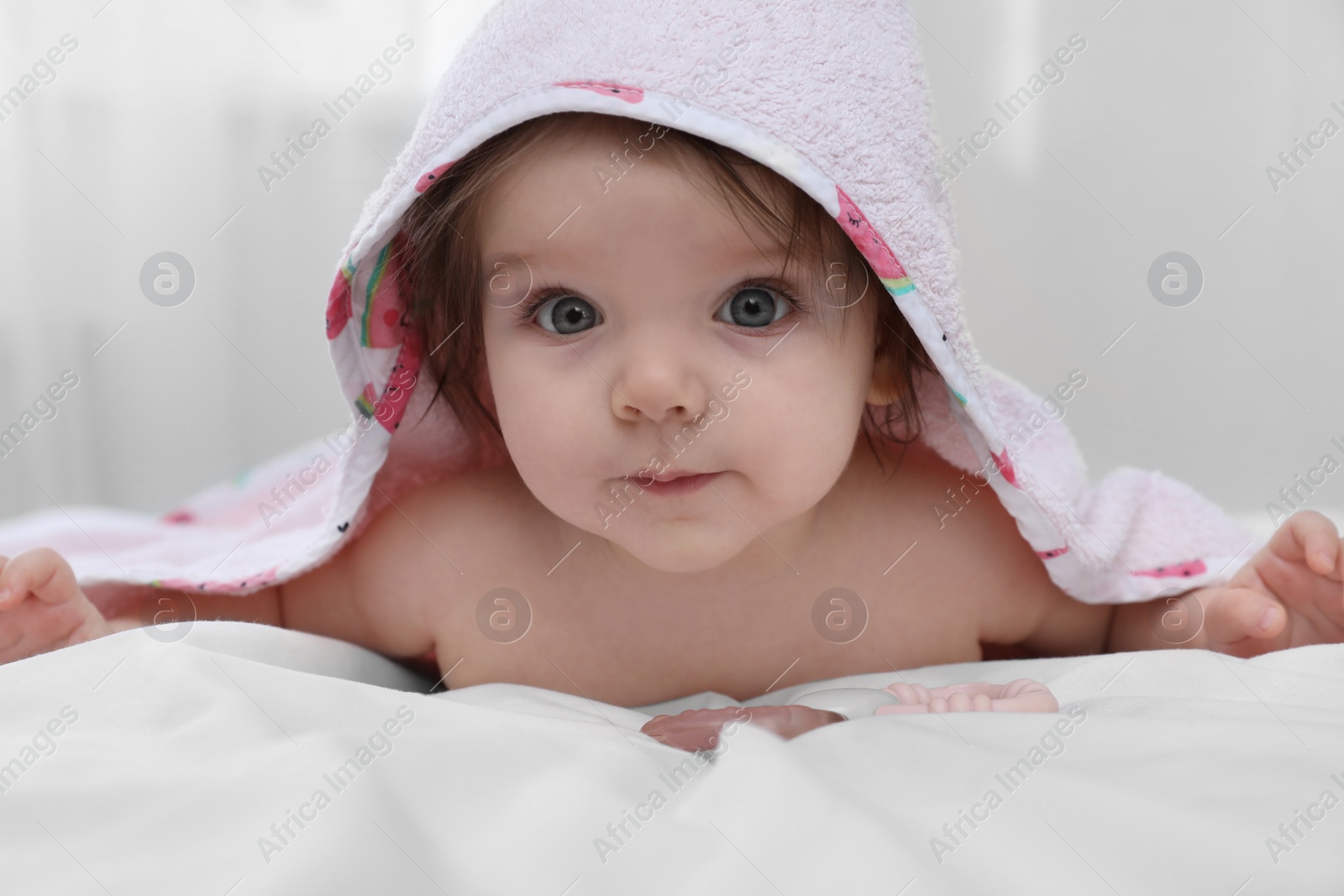 Photo of Cute little baby in hooded towel after bathing on bed at home