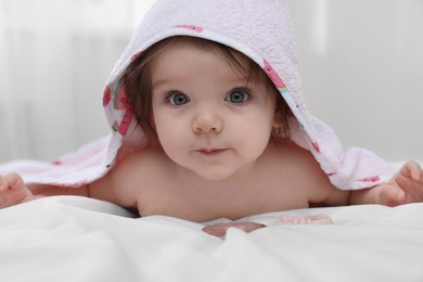 Cute little baby in hooded towel after bathing on bed at home
