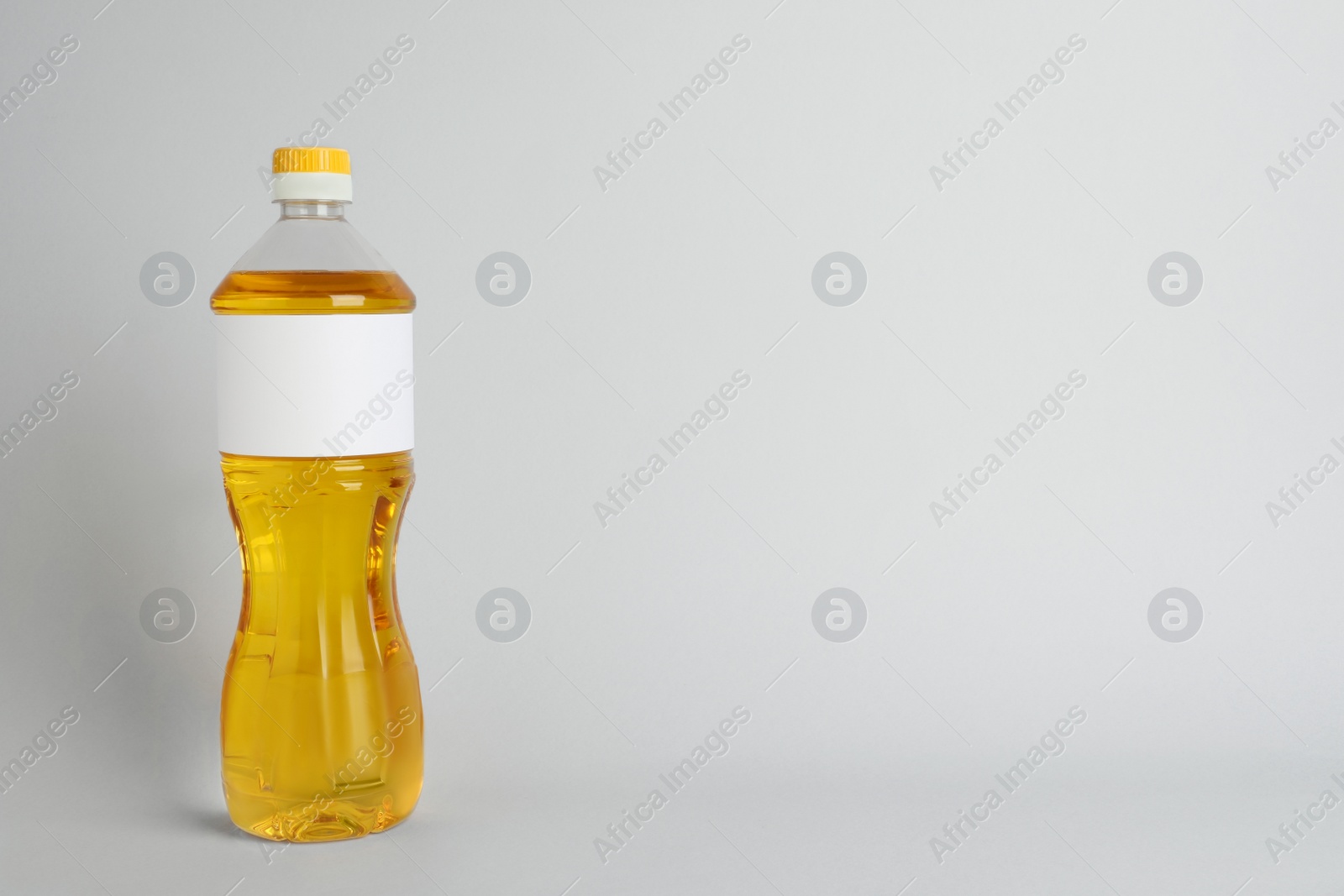 Photo of Bottle of cooking oil on light grey background. Space for text