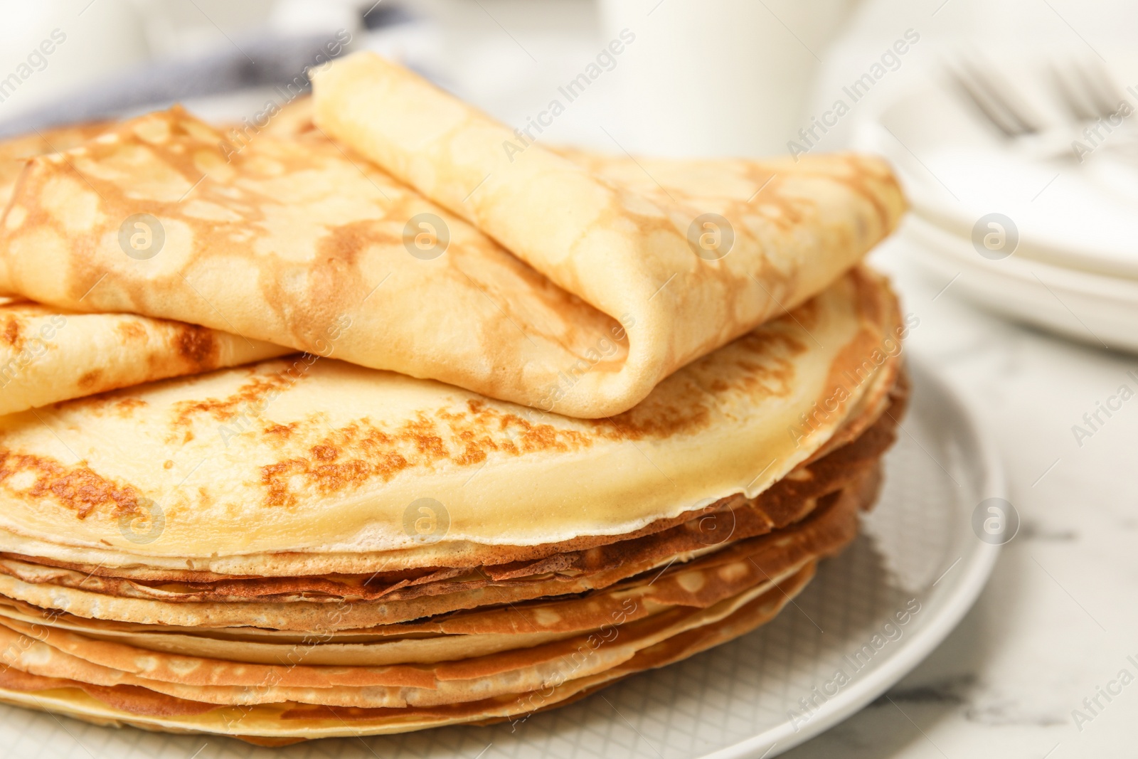 Photo of Stack of fresh thin pancakes on white marble table, closeup