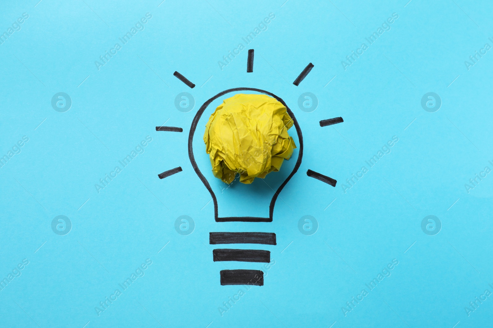 Photo of Idea concept. Light bulb made with crumpled paper and drawing on light blue background, top view