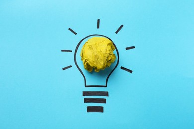 Idea concept. Light bulb made with crumpled paper and drawing on light blue background, top view