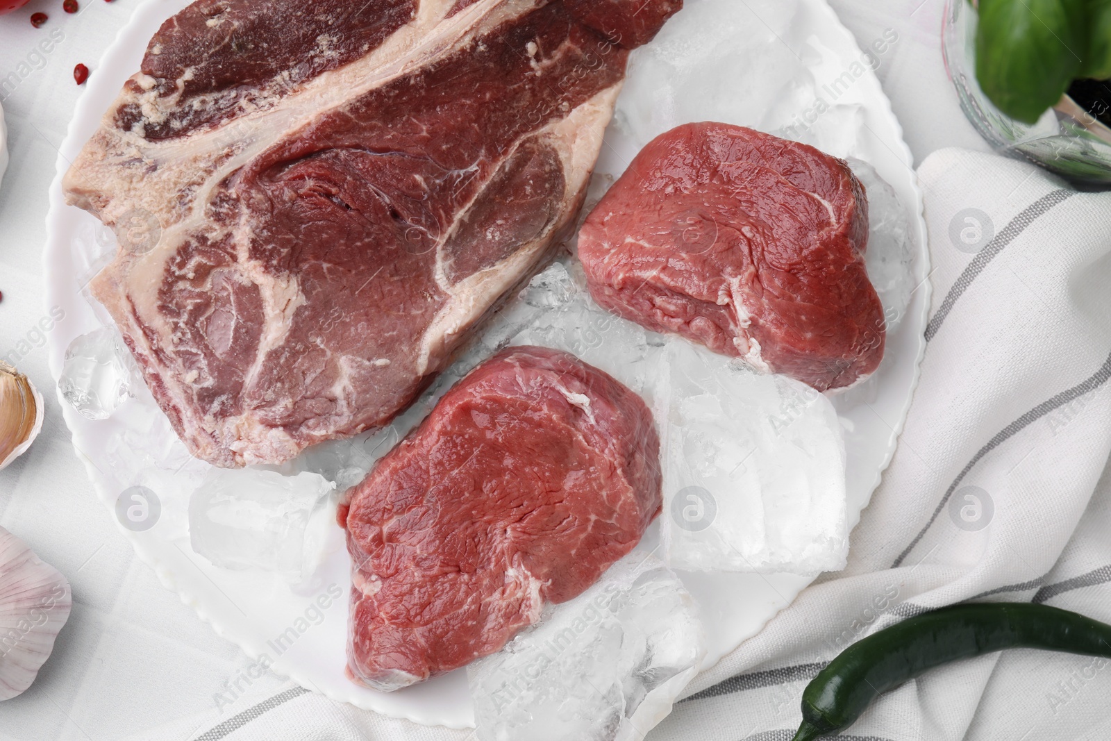 Photo of Fresh raw cut beef and ice cubes on white table, flat lay