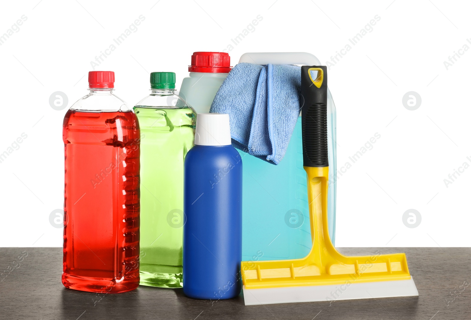 Photo of Bottles, squeegee and car wash cloth on wooden table against white background