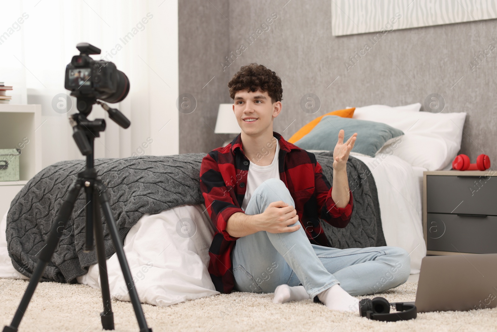 Photo of Smiling teenage blogger explaining something while streaming at home