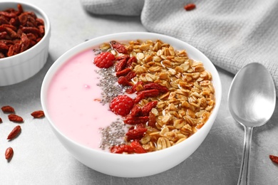 Smoothie bowl with goji berries and spoon on light grey table