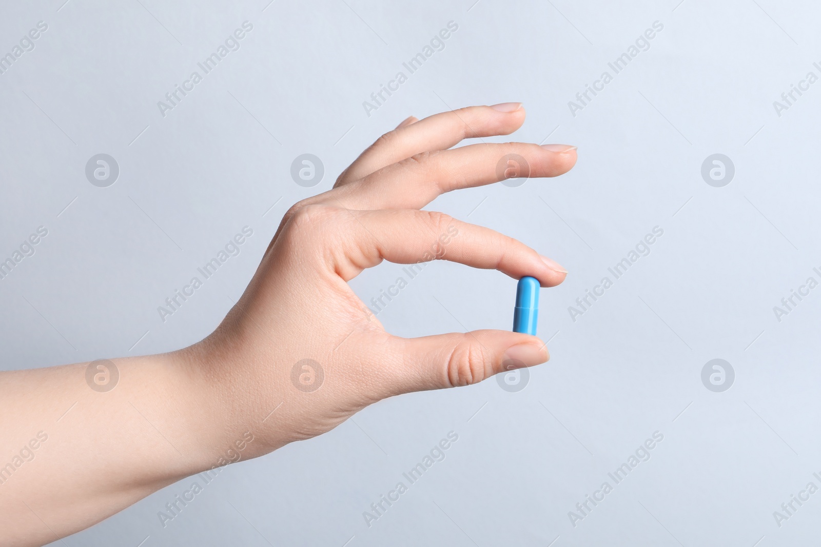 Photo of Woman with pill on light grey background, closeup