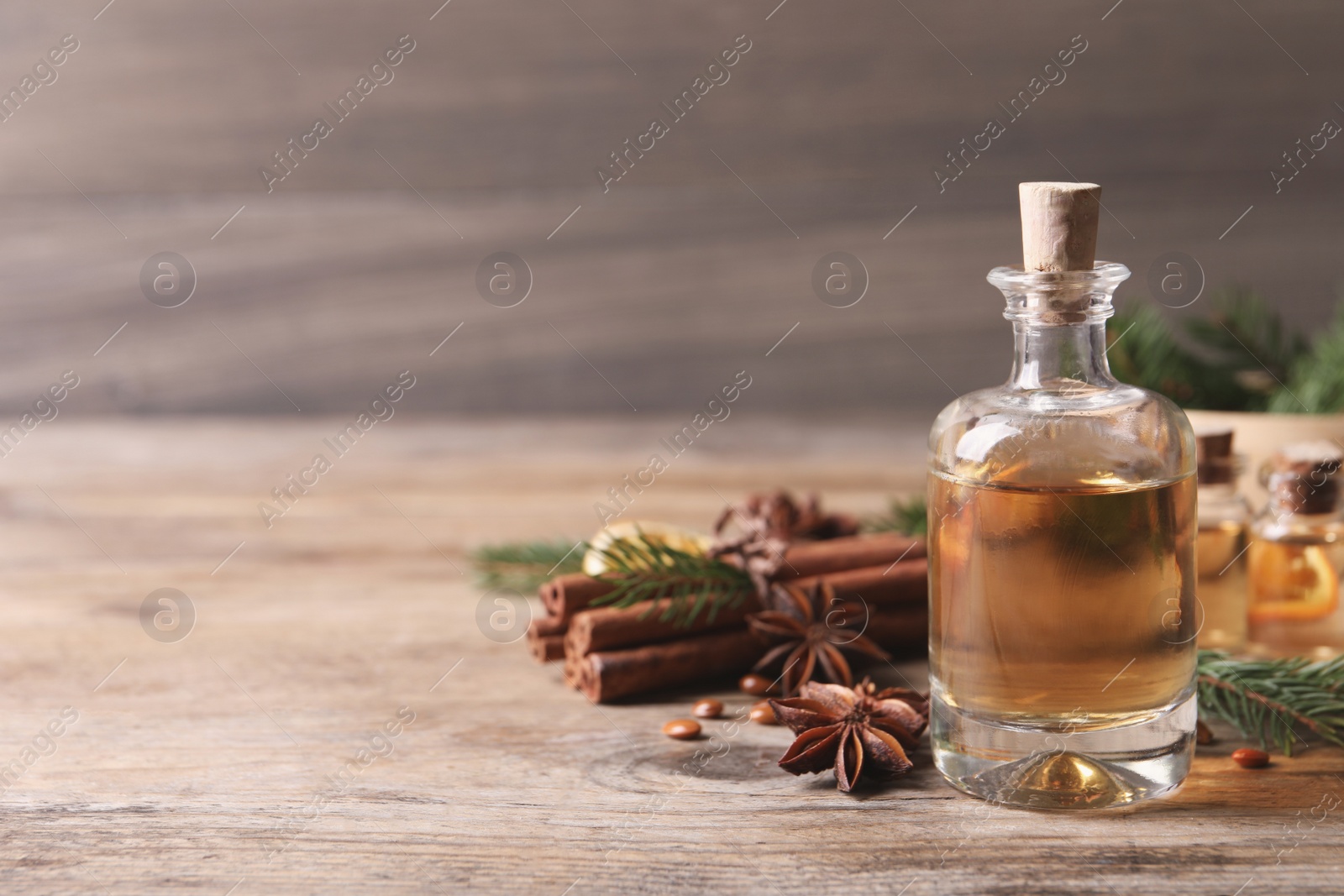 Photo of Anise essential oil and spices on wooden table, space for text