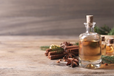 Anise essential oil and spices on wooden table, space for text