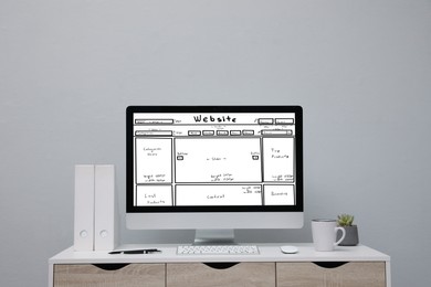 Computer with sketch of website planning and design on white table