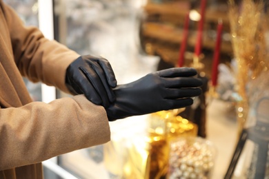 Photo of Woman putting on stylish leather gloves outdoors, closeup of hands