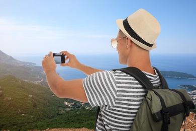 Traveler taking photo of mountains and sea during summer vacation trip