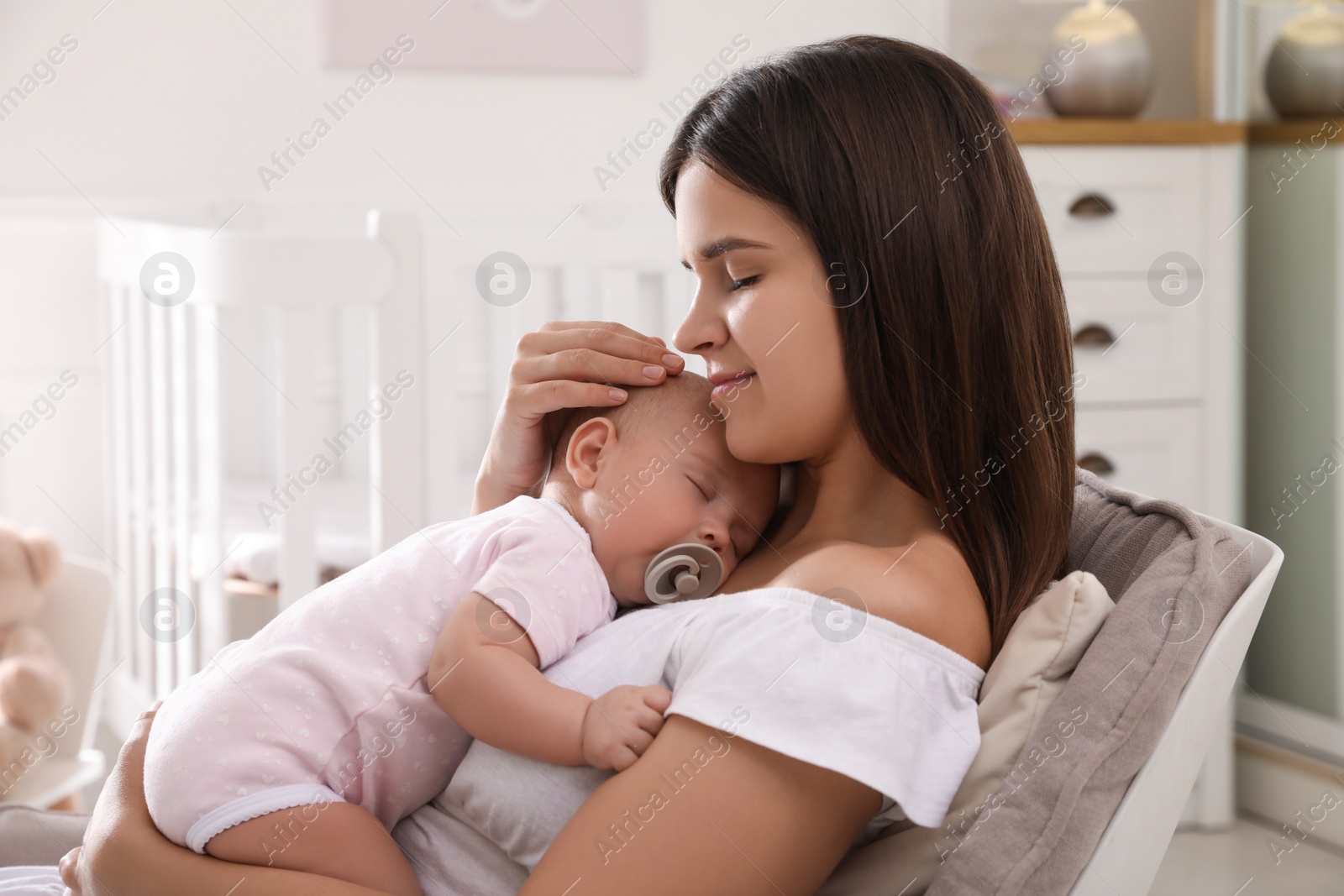 Photo of Happy young mother with her sleeping baby in armchair at home